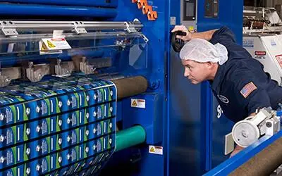 Glenroy flexible packaging manufacturing employee inspecting pouch production equipment on the factory floor